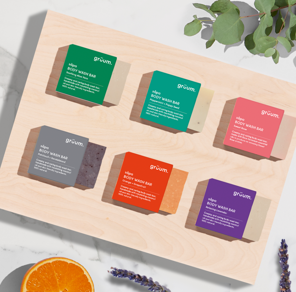 Six colorful body wash bars on wood.