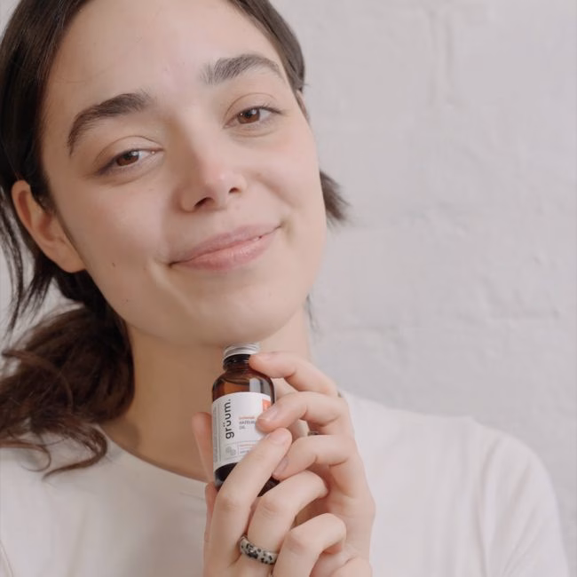 Person holding a serum bottle, smiling.