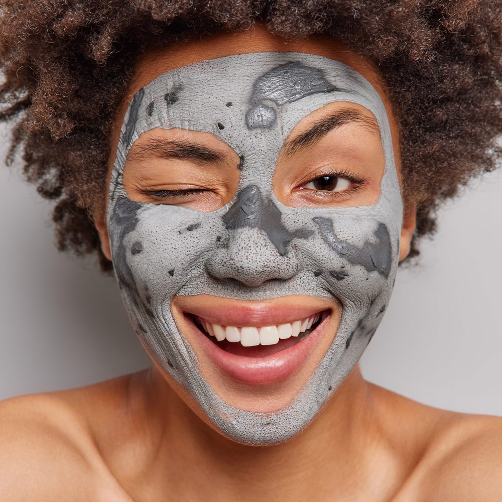 Person winking with clay face mask
