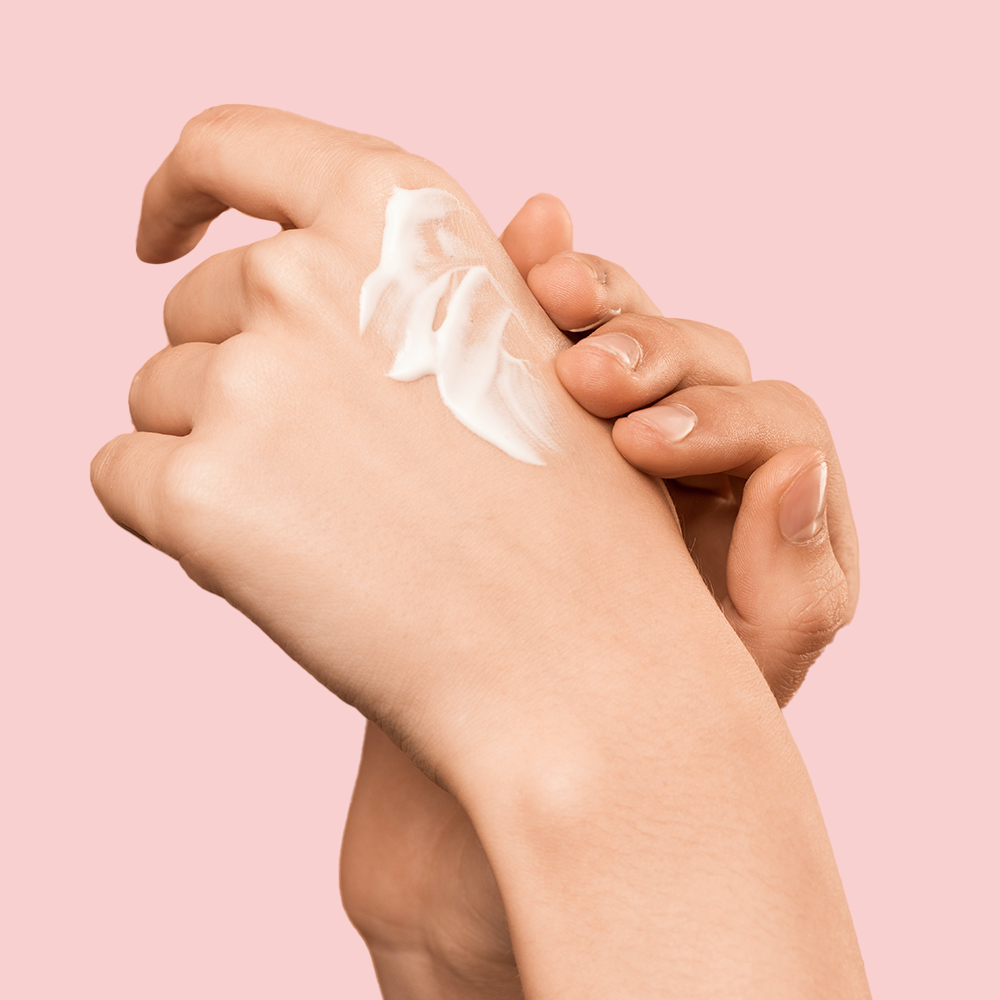 Hands applying cream on skin.
