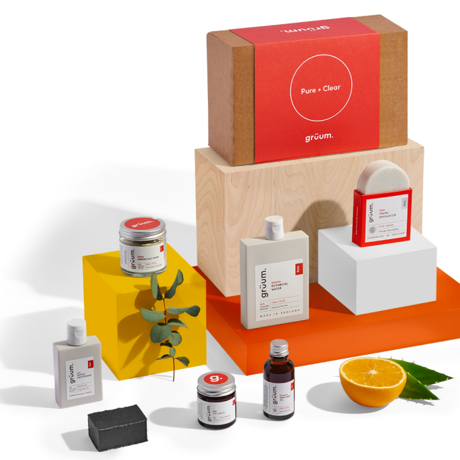 Assorted skincare products with orange and leaf.