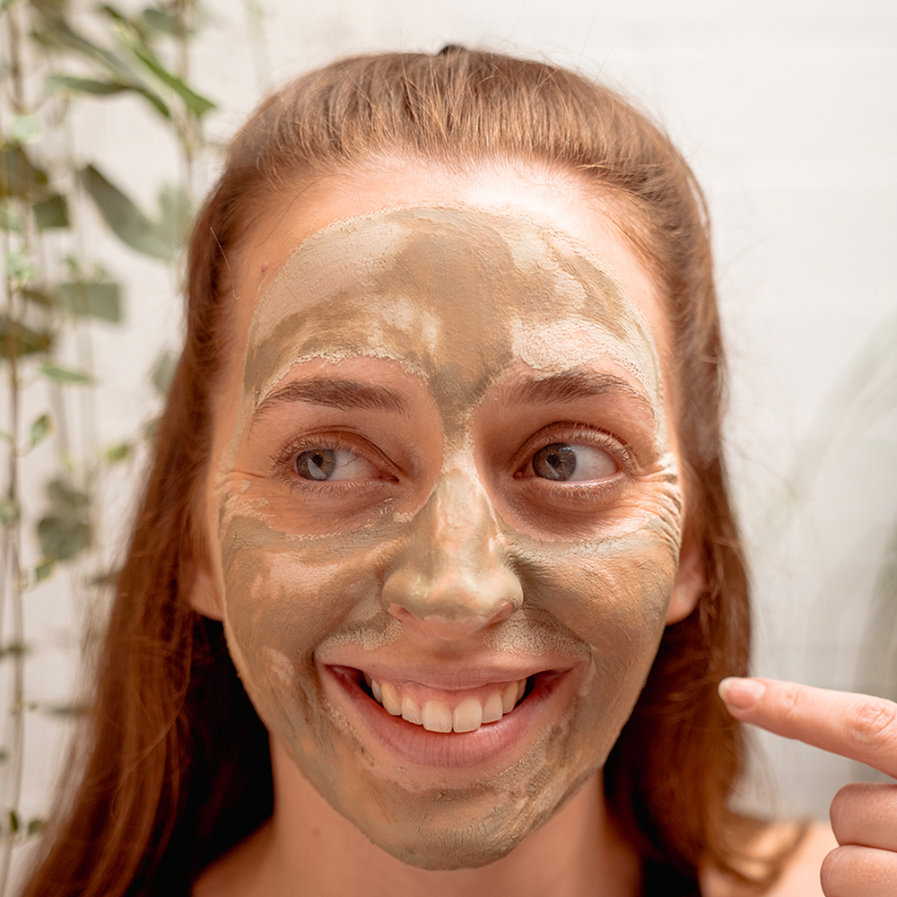 Woman with clay face mask smiling
