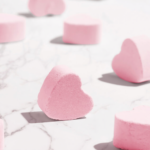 Pink heart-shaped marshmallows on marble surface.
