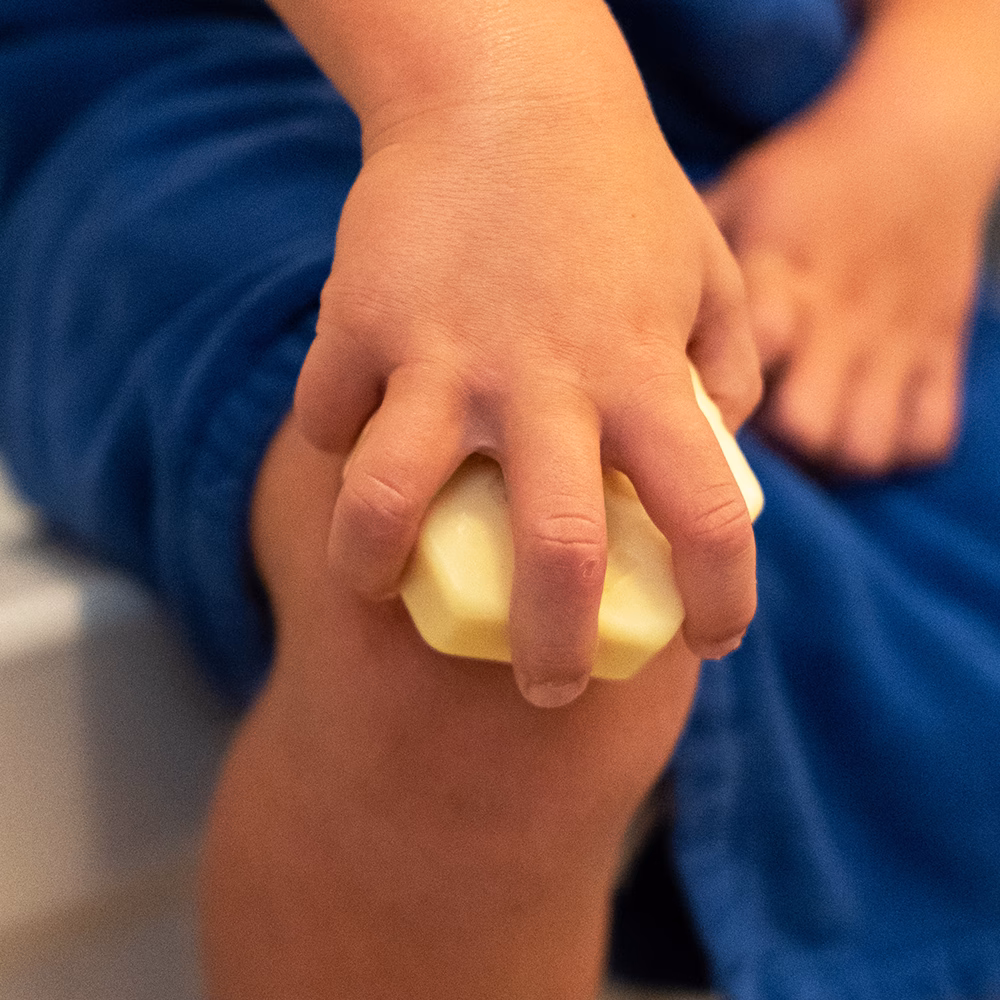 Child holding soap on knee.