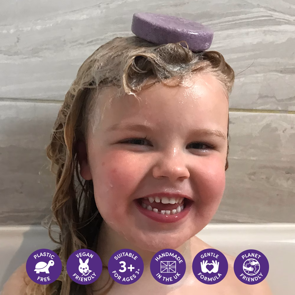 Child with soap on head, smiling.