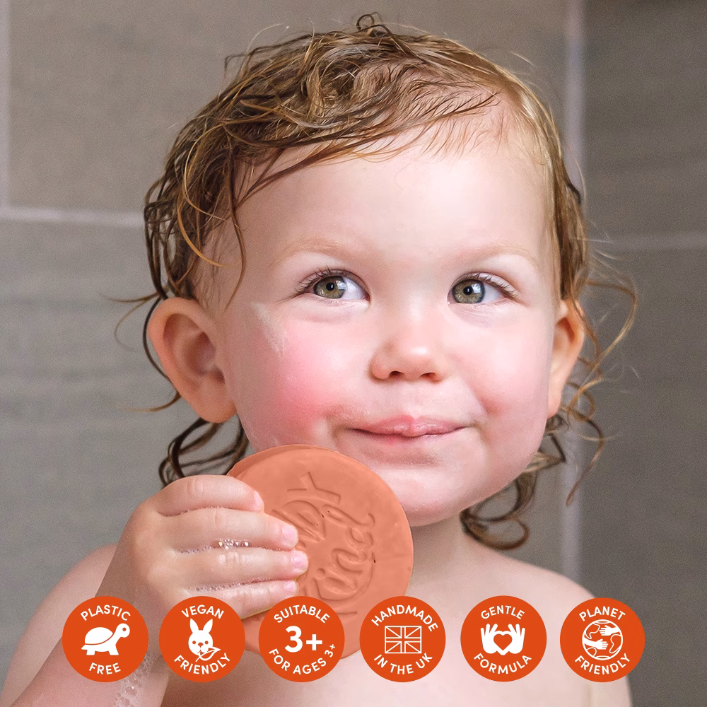 Child holding round soap in bath.