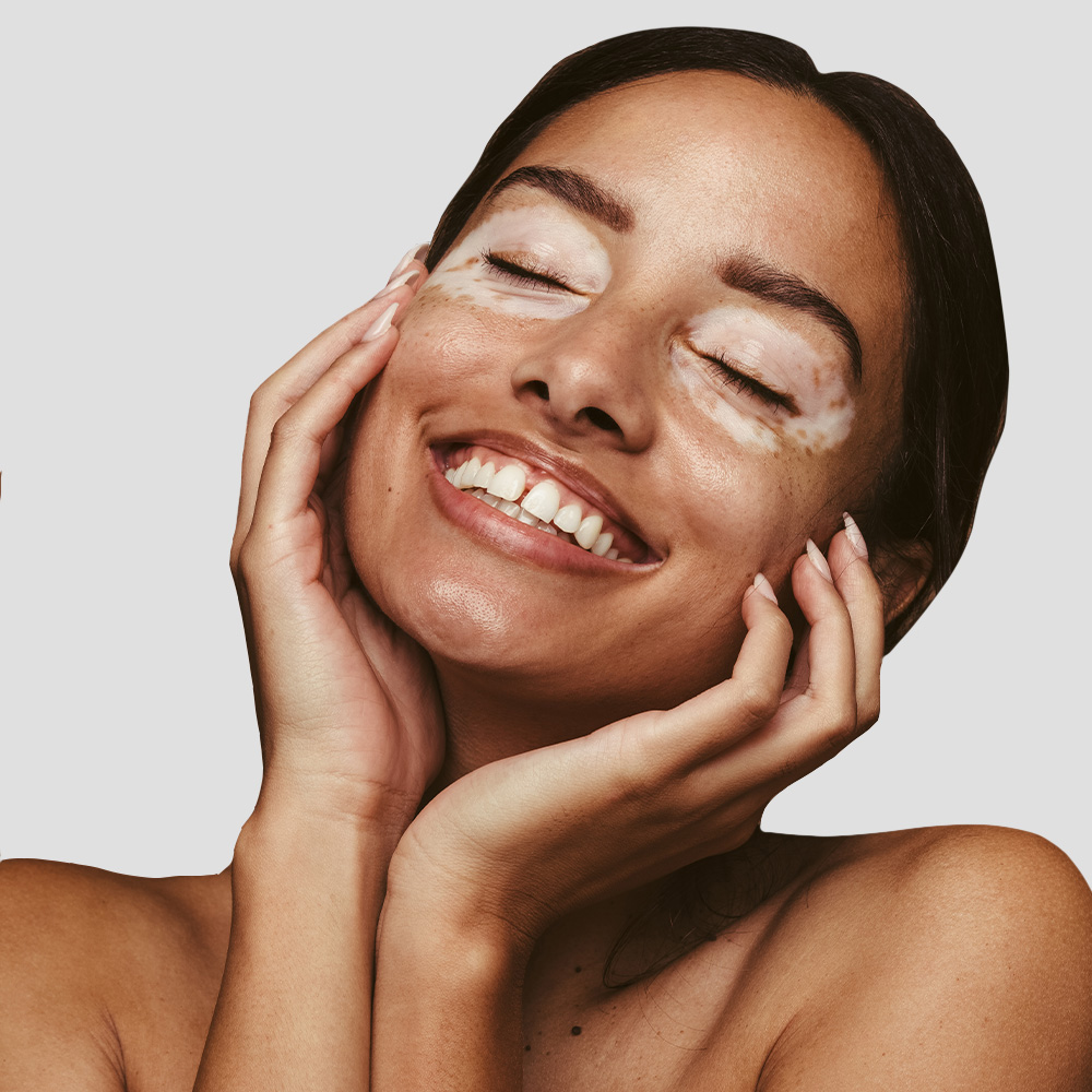 Smiling woman with eyes closed, touching face.