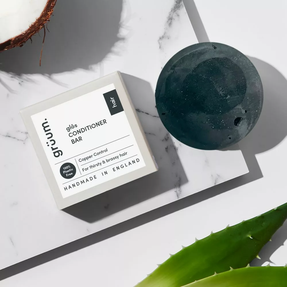 Conditioner bar and soap on marble surface.