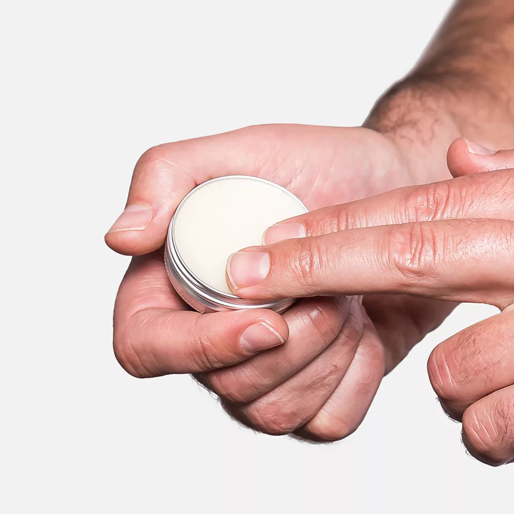 Hands holding a tin of cream.