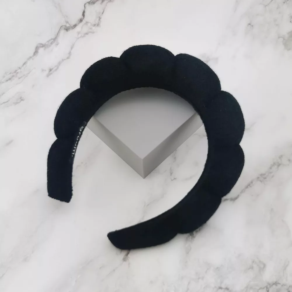 Black scalloped headband on marble surface.