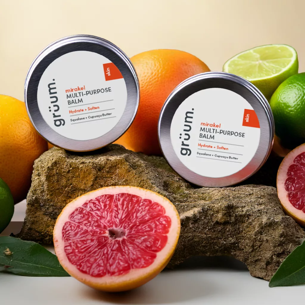 Balm tins with citrus fruits in background.