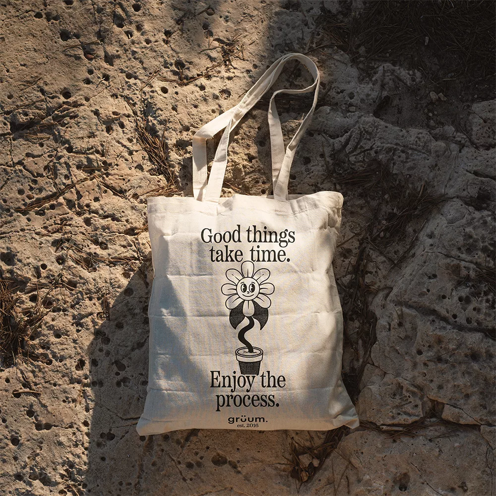 Tote bag on rocky ground with floral design.