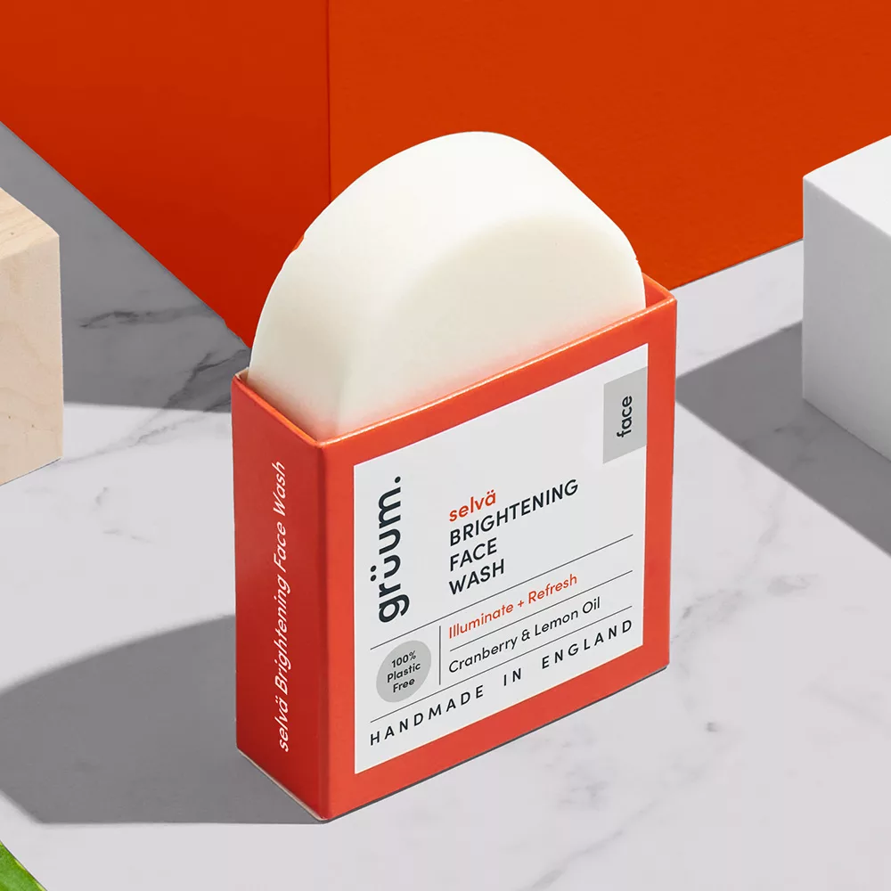 Brightening face wash packaging on marble surface.