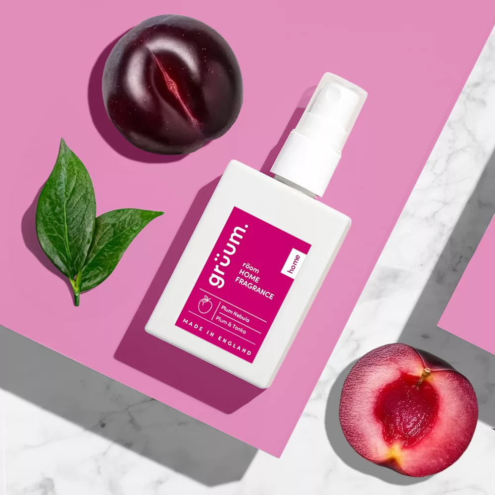 Pink fragrance bottle with fruits and leaves.