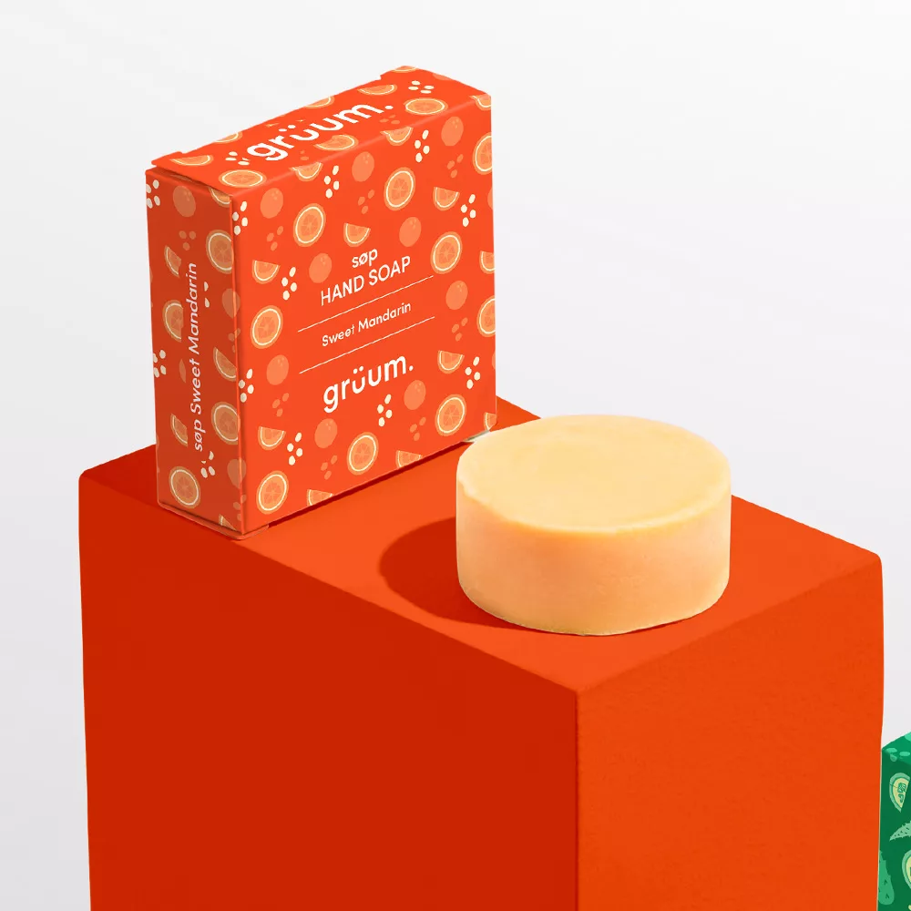 Round soap and orange packaging on red block.