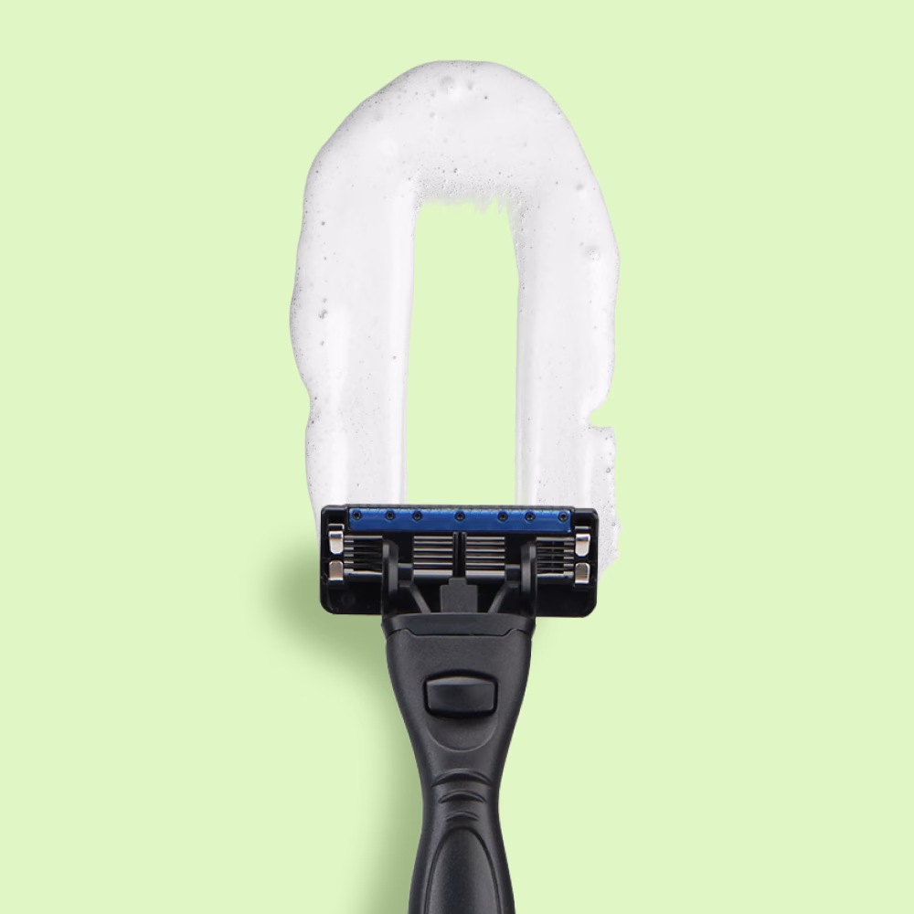 Razor creating foam rectangle on green background.